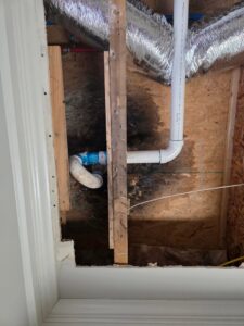 Exposed pipes and ductwork in a wall cavity with visible water stains on the wood, indicating hidden water damage by Restoration Specialist in O Fallon, MO.