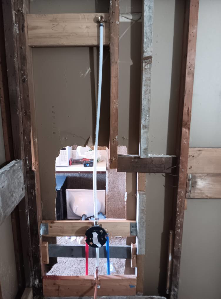 Exposed plumbing pipes and shower valve during water damage repair by Integrity Solutions in Omaha, NE.