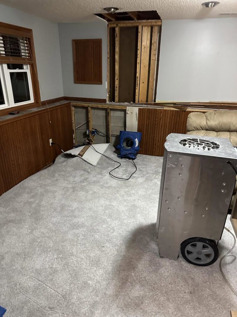 Exposed wall studs and an air mover drying a room after water damage, handled by Restoration Alliance Services in Elk River, MN.