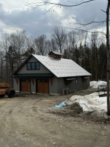 Exterior view of a building featuring two newly installed wooden garage doors by Ski Door, Inc. in Center Rutland, VT.