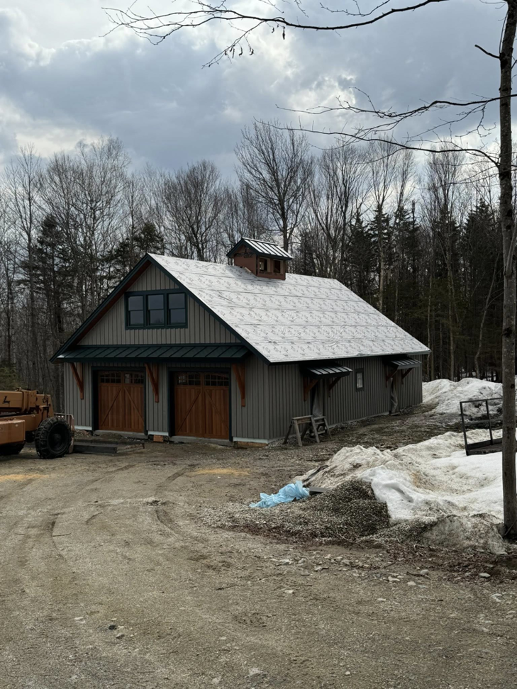 Exterior view of a building featuring two newly installed wooden garage doors by Ski Door, Inc. in Center Rutland, VT.
