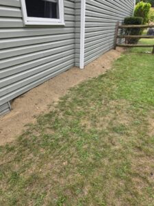 Exterior of a house with fresh dirt backfilled against the foundation after waterproofing by EverDry Toledo in Toledo, OH.