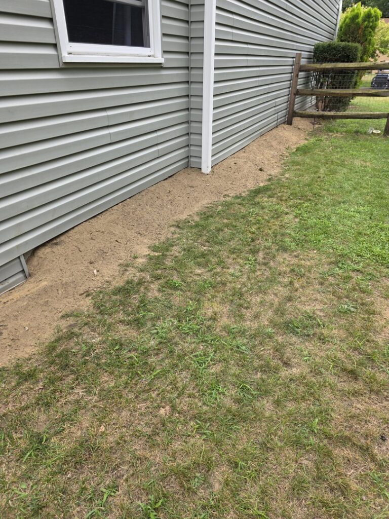 Exterior of a house with fresh dirt backfilled against the foundation after waterproofing by EverDry Toledo in Toledo, OH.