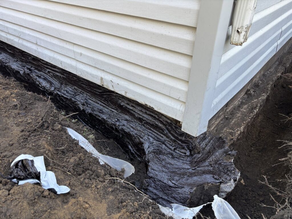 Exterior foundation waterproofing with a dark sealant applied by EverDry Toledo in Toledo, OH.