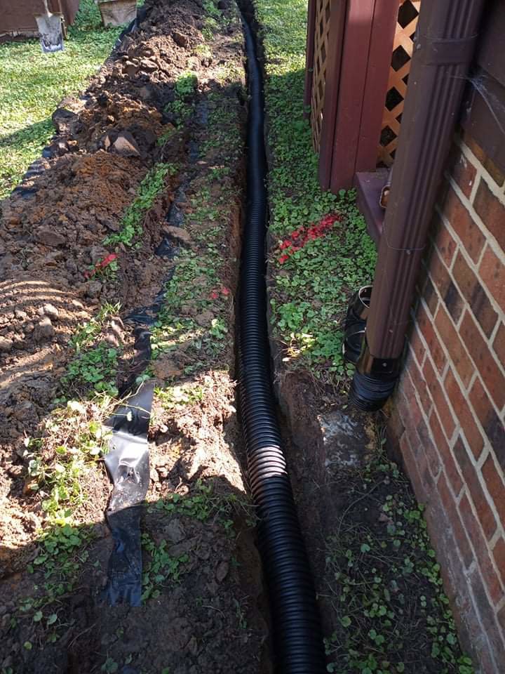 An exterior French drain with corrugated pipe being installed by Tidewater Home Improvement LLC in Hampton, VA.