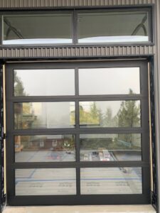 Exterior view of a modern glass garage door with multiple panels and windows installed by Devildog Dock N Door in Helena, MT.