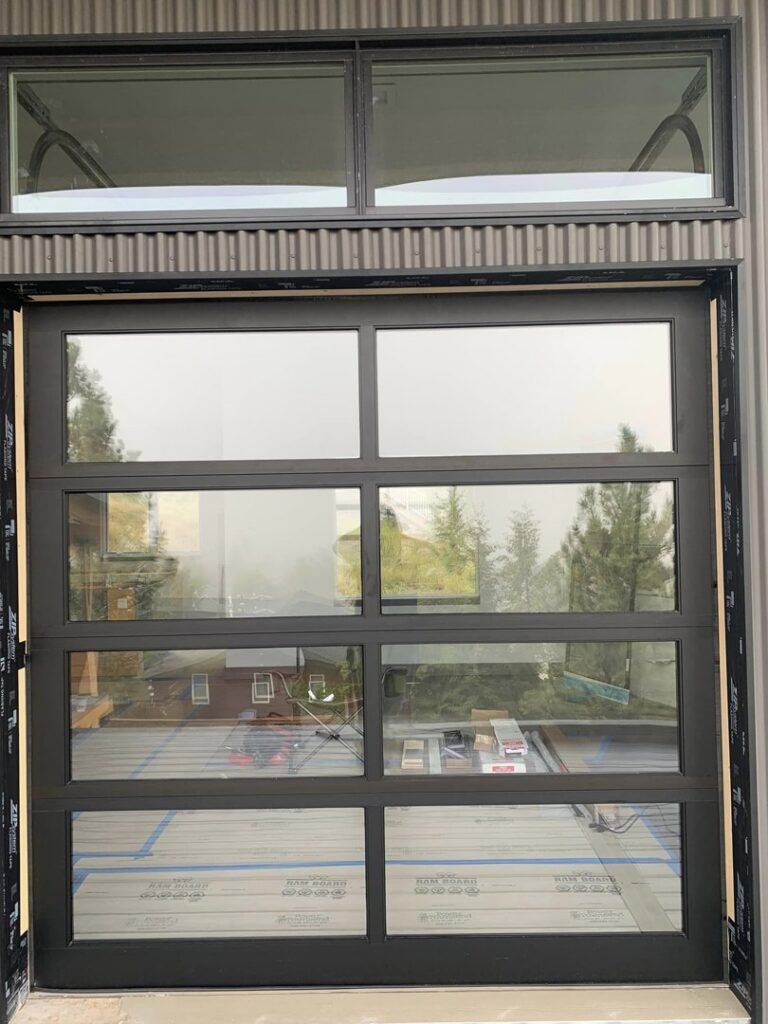 Exterior view of a modern glass garage door with multiple panels and windows installed by Devildog Dock N Door in Helena, MT.