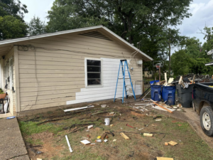 Exterior house siding being removed with debris on the ground by Rayshawn's Home improvement & Construction work in Bossier City, LA.