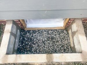 An exterior window well filled with gravel for drainage by Tidewater Home Improvement LLC in Hampton, VA.