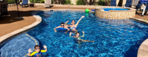 A family enjoying their custom-shaped swimming pool and spa built by NATURAL SALT POOLS LLC in Kailua, HI.