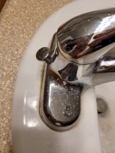 A bathroom faucet covered in hard water stains before cleaning by Ady's Housekeeping in Yakima, WA