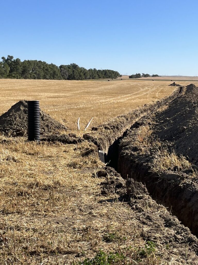 Field drainage and water pipe installation in a trench by KD Services - Excavating in Bismarck, ND