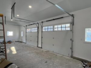 A finished garage interior featuring two white garage doors and openers installed by NDI Garage Door in Plaistow, NH.