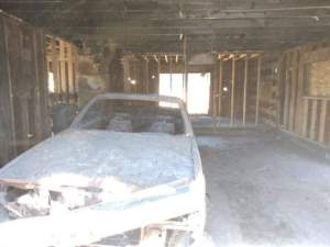 Interior of a fire-damaged building stripped to the studs with a burnt car, showcasing demolition work by Building Assisting Group Demolition INC in Tacoma, WA.