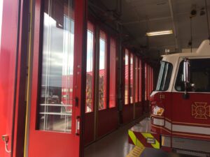 Interior view of a fire station with red glass panel garage doors, a specialty of PS Garage Doors of Williston, ND.