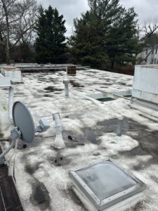 A flat roof with standing water and dark, discolored patches, indicating water damage assessment by Homcertin llc in Trenton, NJ.