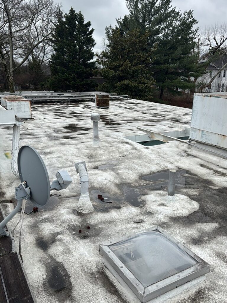 A flat roof with standing water and dark, discolored patches, indicating water damage assessment by Homcertin llc in Trenton, NJ.