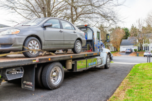 A flatbed tow truck from Select Towing and Recovery transporting a gray sedan in Casper, WY.