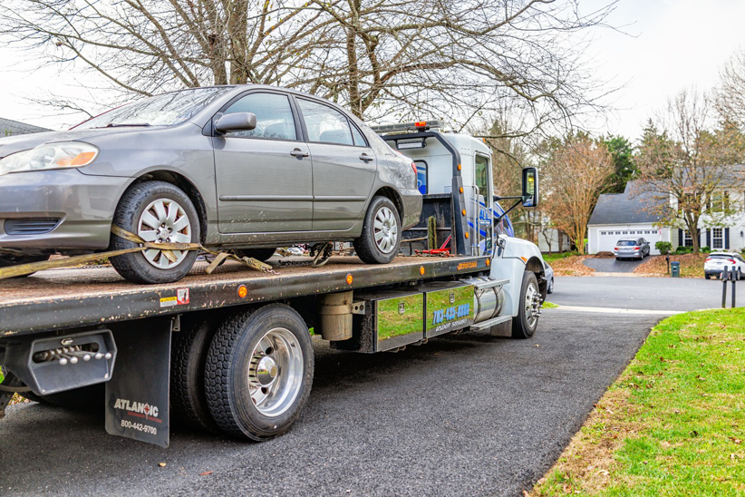 A flatbed tow truck from Select Towing and Recovery transporting a gray sedan in Casper, WY.