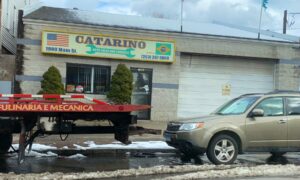 A flatbed tow truck parked outside Catarino Auto Body, ready for towing services in Bridgeport, CT.