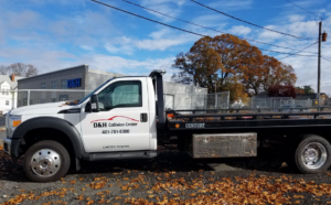 A white flatbed tow truck for D & H Collision Center, ready for towing services in Warwick, RI.