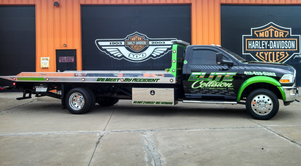 A green and black flatbed tow truck from Elite Collision, ready for towing services in Pittsburgh, PA.