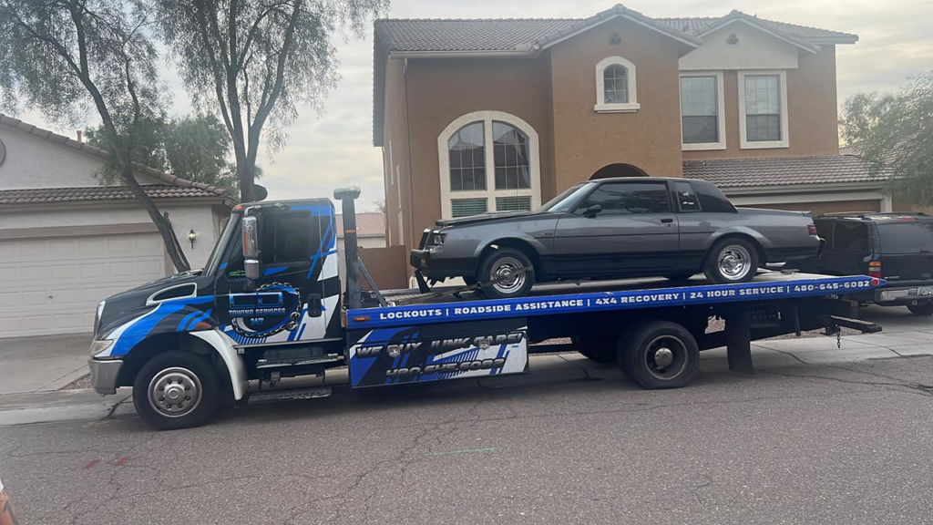 A flatbed tow truck from CnD towing carrying a grey car in Phoenix, AZ.