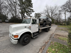 A white flatbed tow truck from Jb's Towing & Recovery hauling a dark SUV in Rossville, GA.