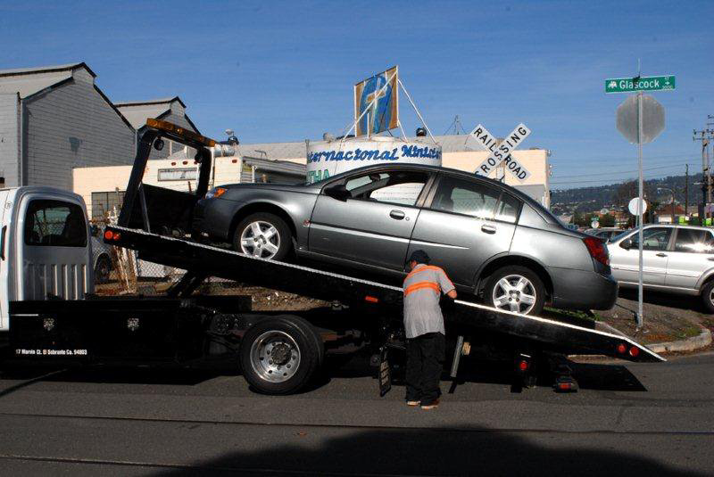 A flatbed tow truck operator loading a grey car on a street for Emergency Towing San Francisco in San Francisco, CA.