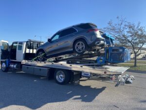 A flatbed tow truck from Jim & Ron's Service Inc. loading a grey SUV in Sioux Falls, SD.
