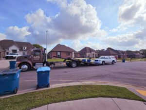 A flatbed tow truck from Rosco's Towing Services LLC loading a white SUV in a residential neighborhood in Carencro, LA.