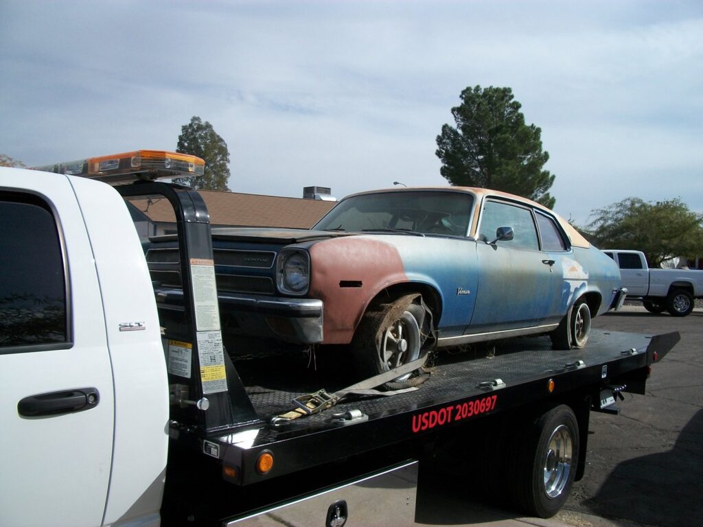 A flatbed tow truck transporting an old car for AE Recovery and Towing in Phoenix, AZ.