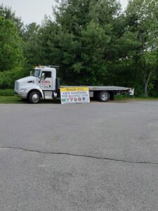 A flatbed tow truck from Bailey's Towing and Auto Body, LLC with a 'Move Over' safety banner in Merrimack, NH.