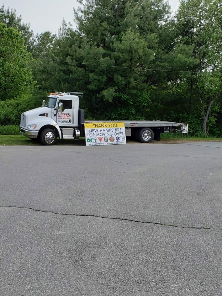 A flatbed tow truck from Bailey's Towing and Auto Body, LLC with a 'Move Over' safety banner in Merrimack, NH.