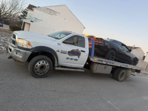 A white flatbed tow truck from Danny's Towing Edgar towing a black car in Indianapolis, IN.