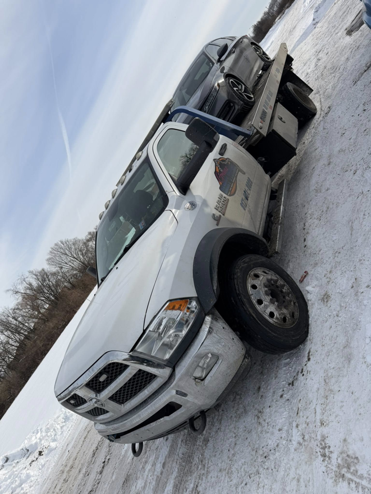 A white flatbed tow truck from Danny's Towing Edgar towing a car in a snowy environment in Indianapolis, IN.