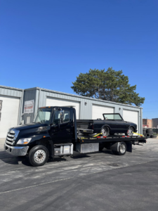 A black flatbed tow truck from A&R towing LLC transporting a black convertible car in Nampa, ID.