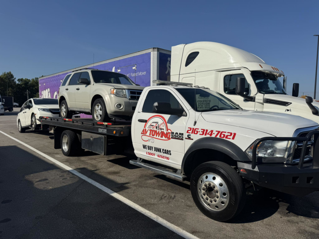 A flatbed tow truck from Av towing llc towing a white SUV and a white car in Cleveland, OH.