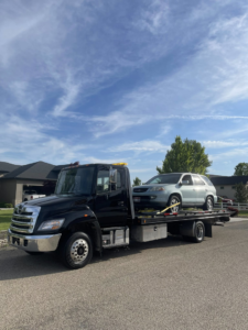 A black flatbed tow truck from A&R towing LLC transporting a light-colored SUV in Nampa, ID.