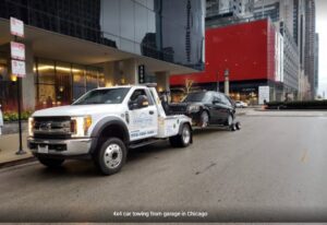 A flatbed tow truck from Chicago Towing towing a black SUV with a wheel lift in Chicago, IL.
