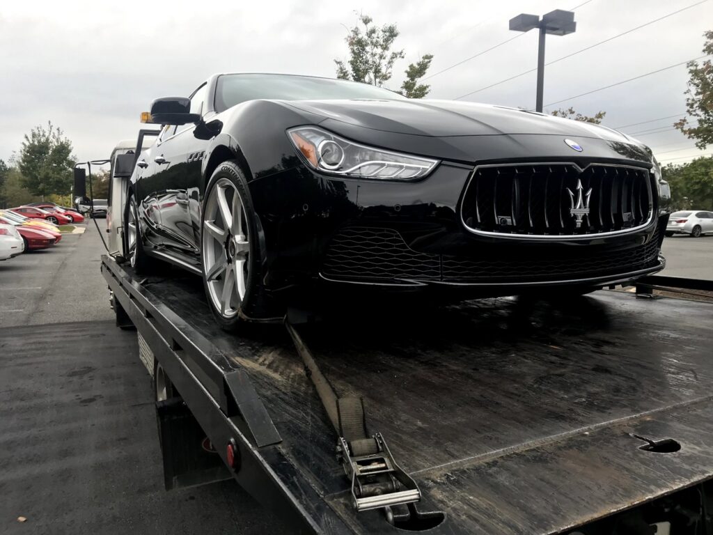 A flatbed tow truck from Andre's Towing Services, LLC transporting a black luxury car in Marietta, GA.