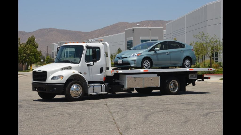 A flatbed tow truck transporting a car, providing reliable towing services from 724 Mobile Mechanic Las Vegas in Las Vegas, NV.