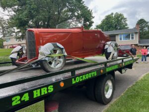 A flatbed tow truck from A and D Towing is transporting a classic red hot rod in Little Ferry, NJ.