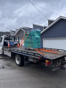 A flatbed tow truck from Chicago Towing transporting a large, wrapped piece of equipment in Chicago, IL.