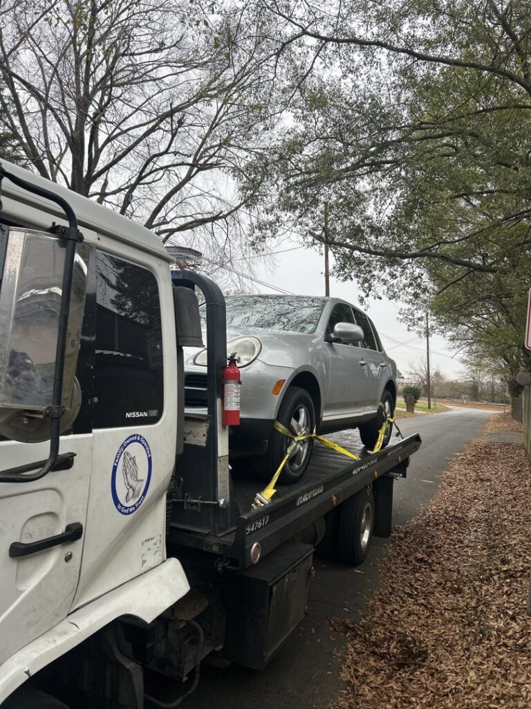 A white flatbed tow truck from Andre's Towing Services, LLC transporting a silver SUV in Marietta, GA.