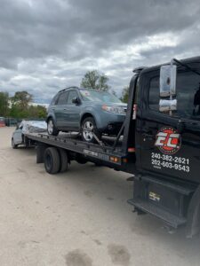 An E.C. Towing, Inc. flatbed tow truck transporting a grey SUV in Gaithersburg, MD.