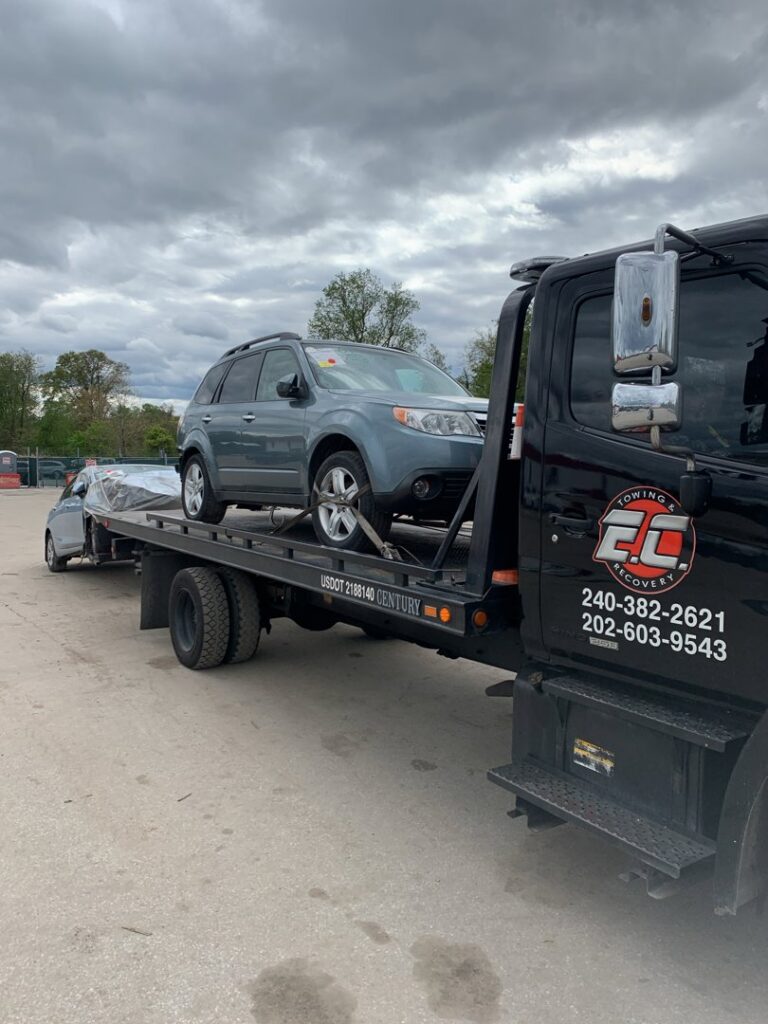 An E.C. Towing, Inc. flatbed tow truck transporting a grey SUV in Gaithersburg, MD.