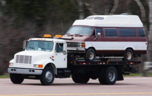 A flatbed tow truck transporting a classic van for Rapt Roadside & Towing Services in Jacksonville, FL.
