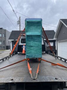 A flatbed tow truck from Chicago Towing transporting a large, wrapped piece of equipment in Chicago, IL.