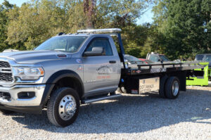 A gray RAM flatbed tow truck parked on a gravel lot at Two Guys Automotive Repair in Clarksville, TN